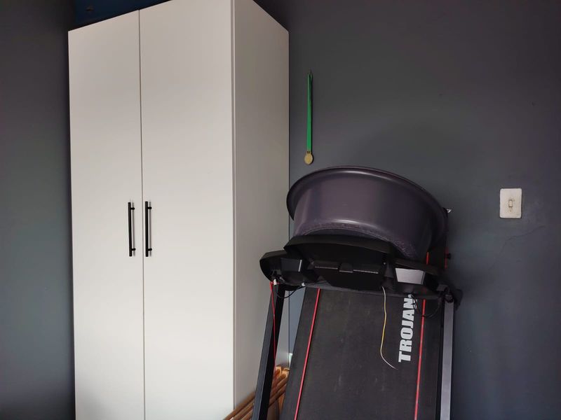 A bedroom featuring a white built-in wardrobe against a dark grey wall.