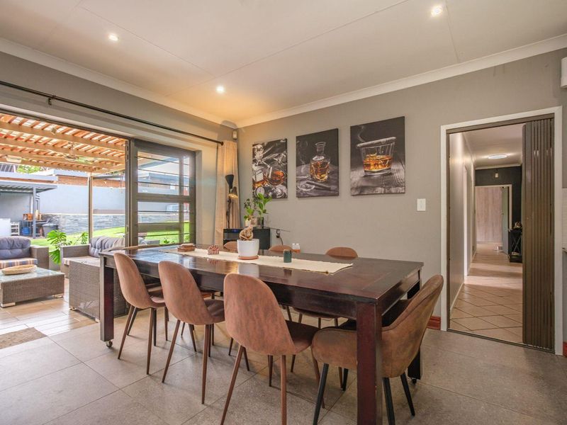 A well-lit dining room featuring tiled flooring, recessed downlights, and large sliding glass doors that provide seamless access to the outdoor patio area.