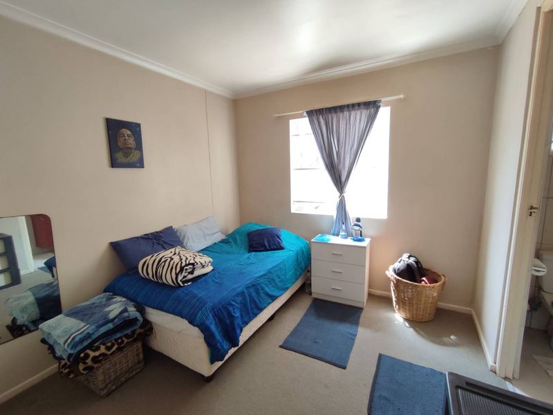 A standard bedroom featuring carpeted flooring and a window with a curtain rod, offering a functional space for rest.