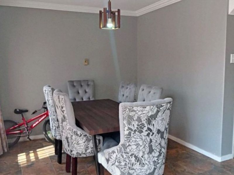 A dining area featuring tiled flooring, crown molding, and a central pendant light fixture.
