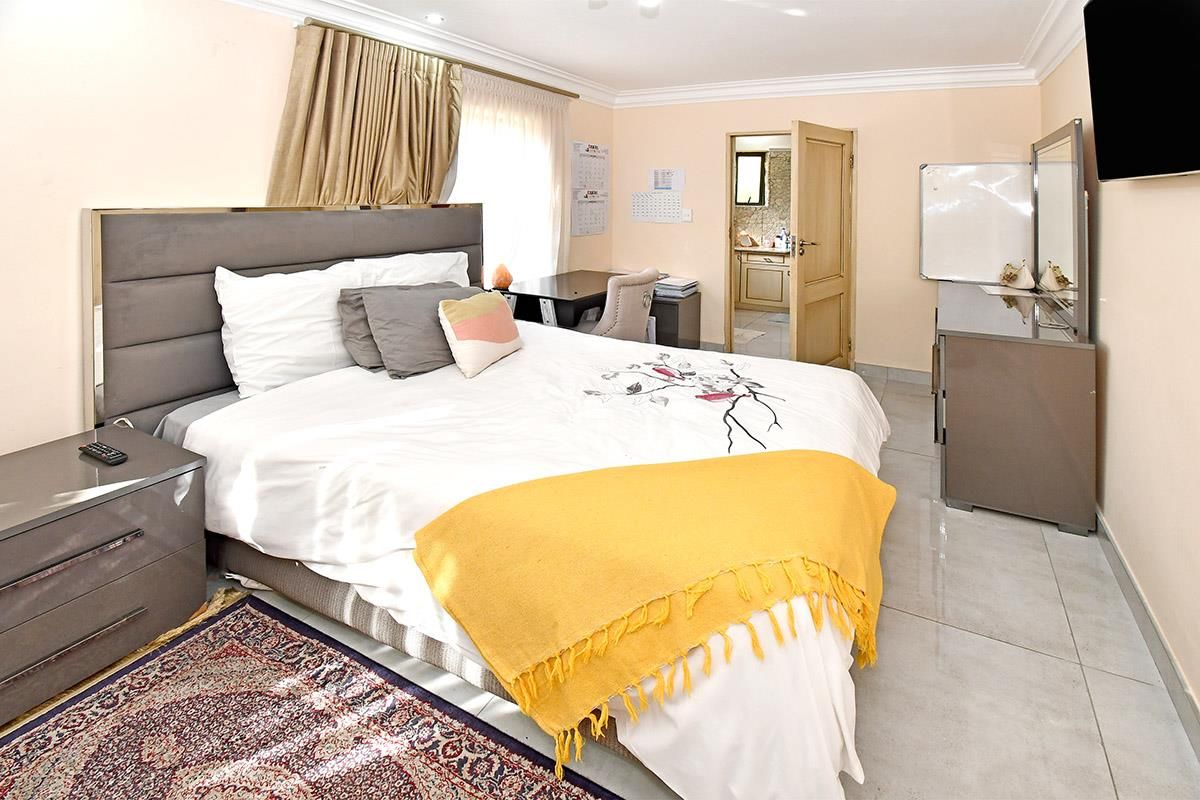 A well-maintained bedroom featuring tiled flooring, coved ceilings, and an en-suite bathroom access point.