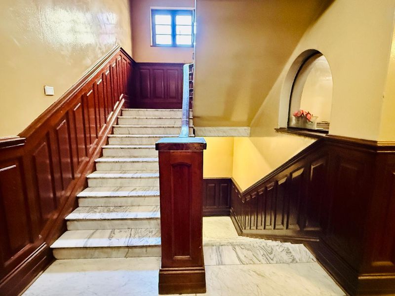 A grand interior hallway featuring a classic marble staircase with ornate wooden wainscoting and a decorative arched wall niche.
