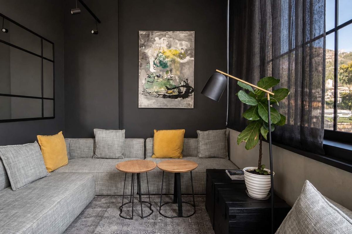 A modern, stylish living area featuring dark charcoal walls, industrial-style steel-framed windows, and recessed track lighting, offering a sophisticated and contemporary aesthetic.