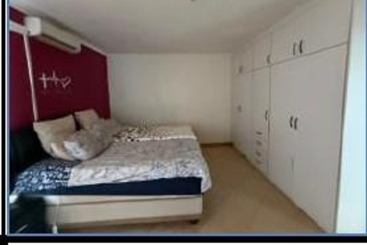 A bedroom featuring built-in floor-to-ceiling wardrobes and a wall-mounted air conditioning unit.