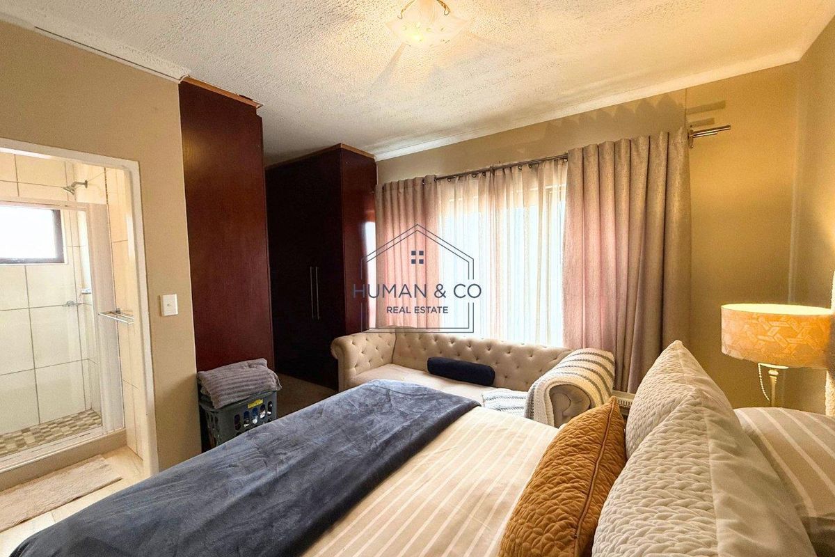 A bedroom featuring built-in dark wood wardrobes and an en-suite bathroom with a shower enclosure.