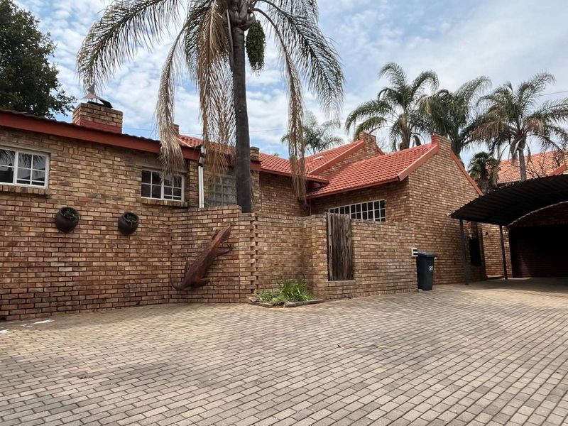 A well-maintained face brick house featuring a tiled roof, paved driveway, and a convenient carport, showcasing classic architectural character.
