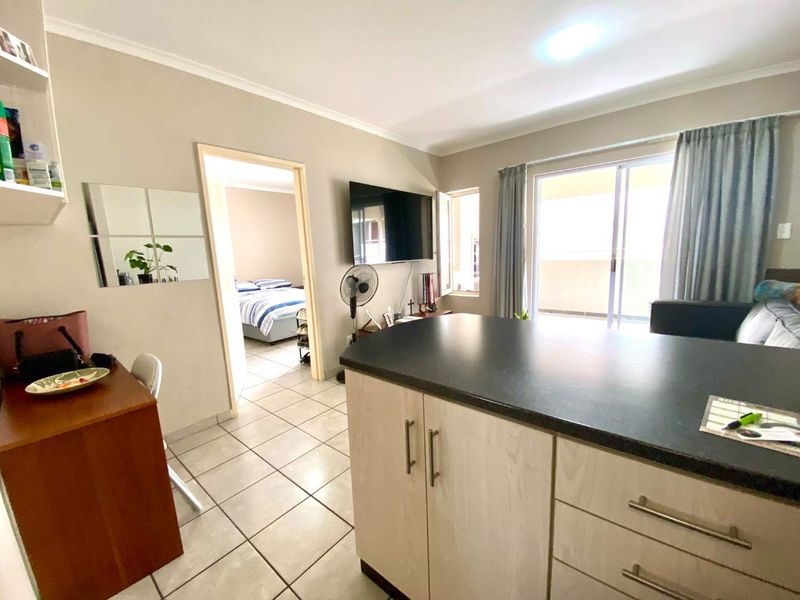 Open-plan living area featuring a kitchen island with dark countertops, tiled flooring, and a sliding door leading to an outdoor balcony.
