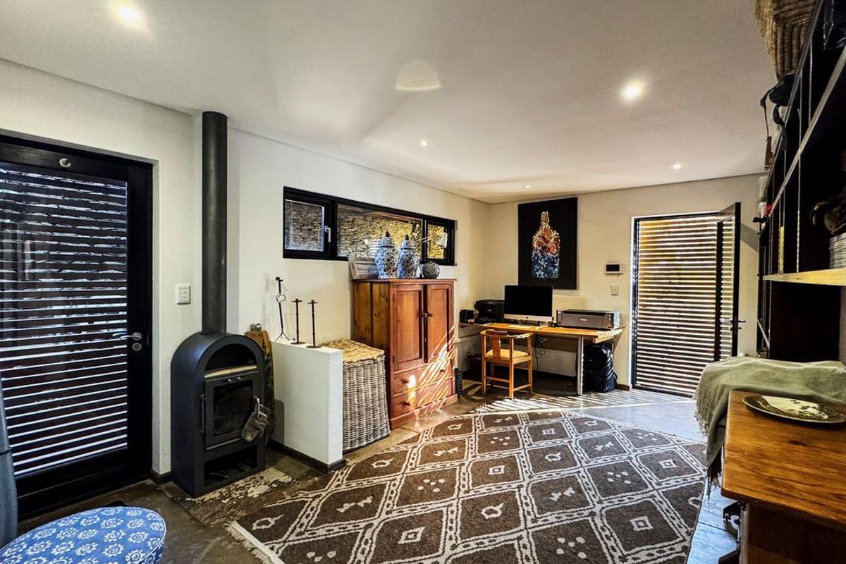 A versatile living space featuring a modern freestanding fireplace, recessed lighting, built-in shelving, and polished concrete flooring with dual access to outdoor areas.