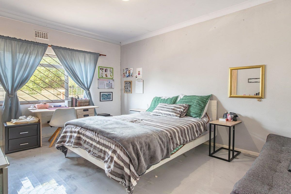 A functional bedroom featuring a window with security bars, coving, and neutral wall finishes, offering a blank canvas for potential updates and modernization.