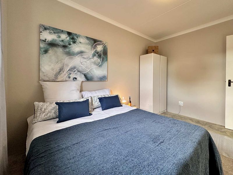 A well-maintained bedroom featuring neutral wall tones, cove cornicing, and a functional layout with built-in storage space.