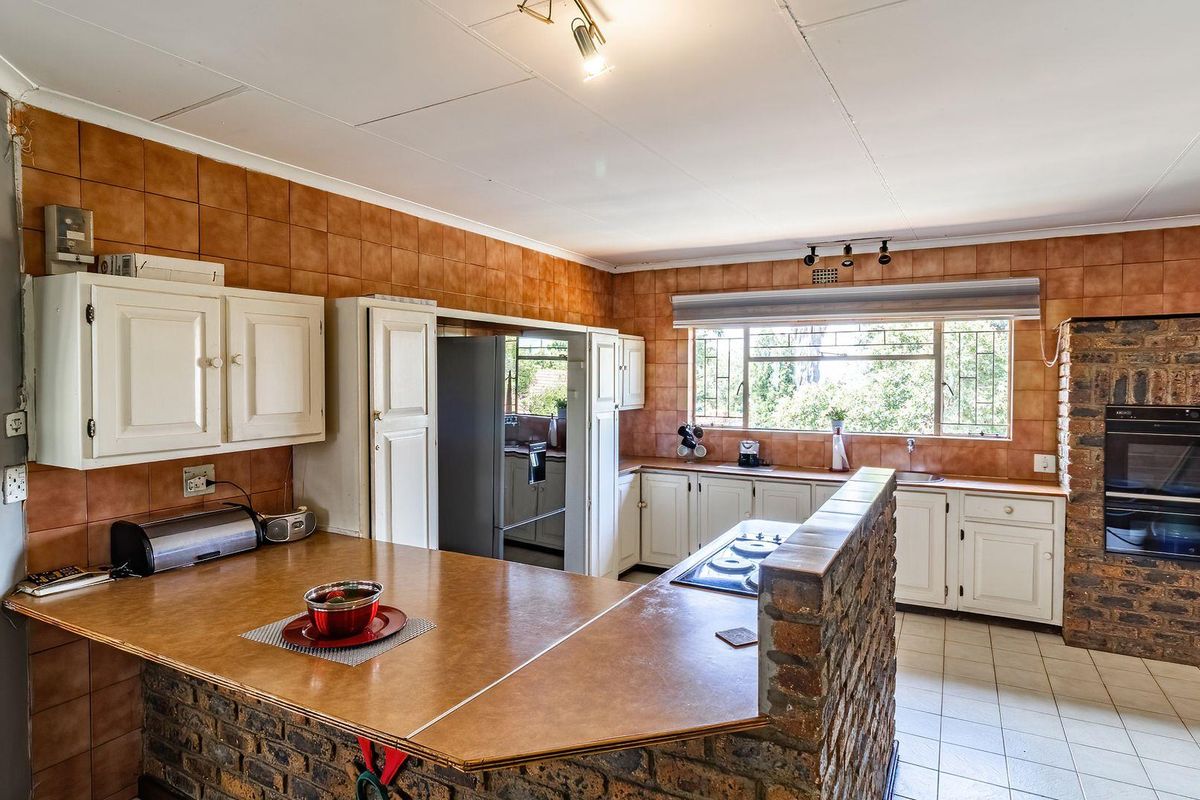 A spacious kitchen featuring a brick-base breakfast bar, built-in oven, ample cabinetry, and large windows providing natural light.