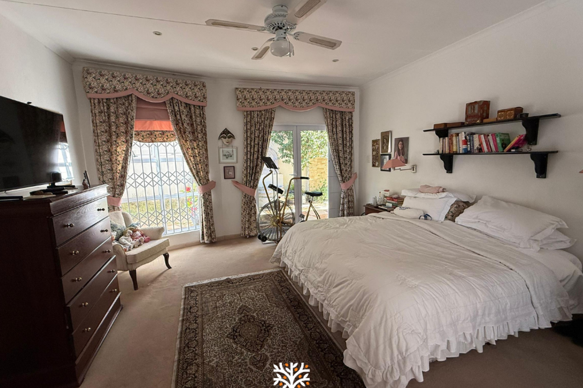 Spacious bedroom featuring a ceiling fan, carpeted flooring, and direct access to the outdoor area through glass sliding doors with security gates.