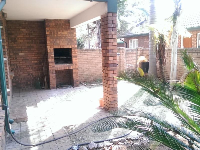 Covered outdoor patio featuring a built-in brick braai and paved flooring, providing a functional space for outdoor entertaining.