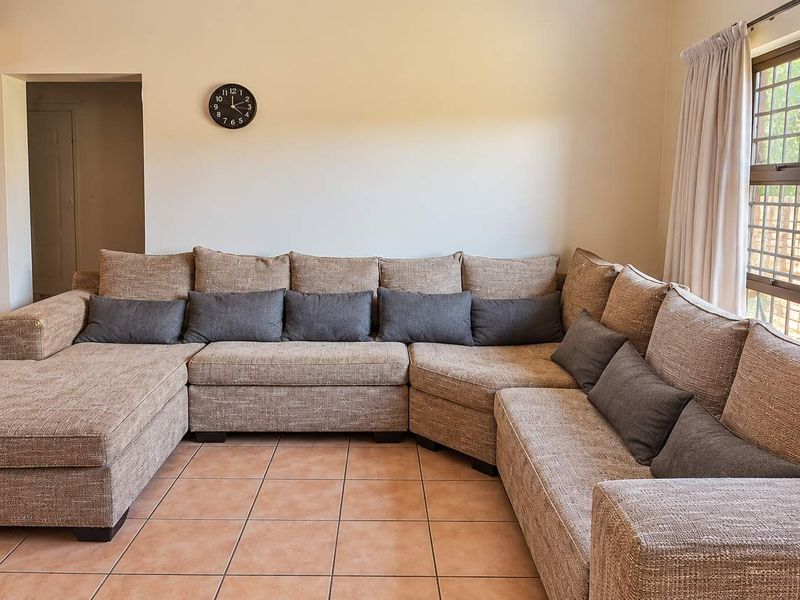 Spacious living room featuring tiled flooring, exposed timber ceiling beams, and a large sliding glass door providing access to the outdoor area.