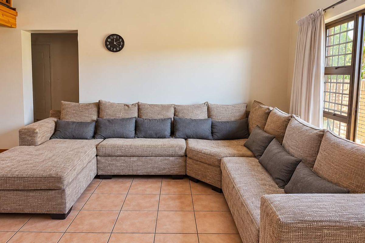 Spacious living room featuring tiled flooring, exposed timber ceiling beams, and a large sliding glass door providing access to the outdoor area.