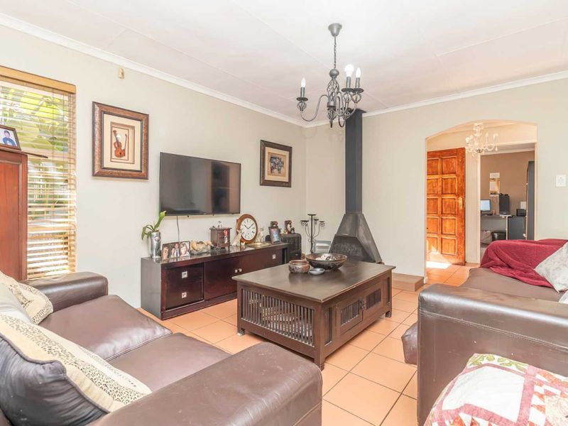 A comfortable living room featuring tiled flooring, a central freestanding fireplace, and a classic chandelier, providing a warm and inviting atmosphere.