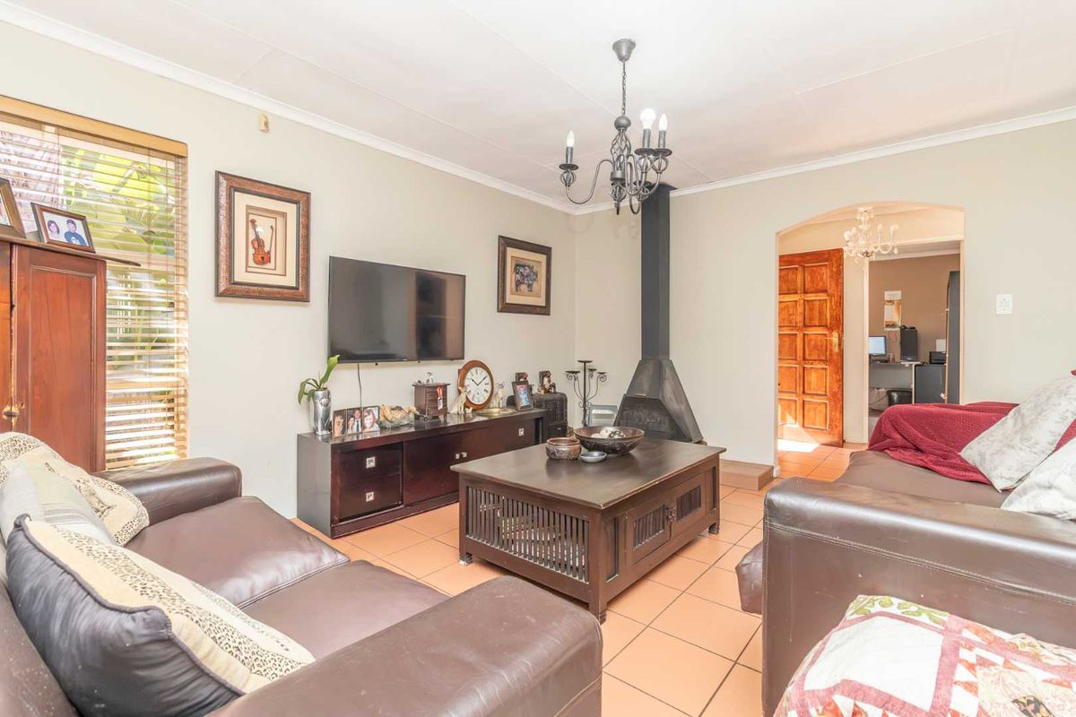 A comfortable living room featuring tiled flooring, a central freestanding fireplace, and a classic chandelier, providing a warm and inviting atmosphere.