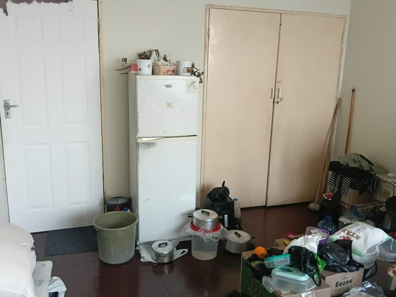 A bedroom featuring built-in cupboards and a standard internal door, currently showing signs of significant wear and requiring maintenance.