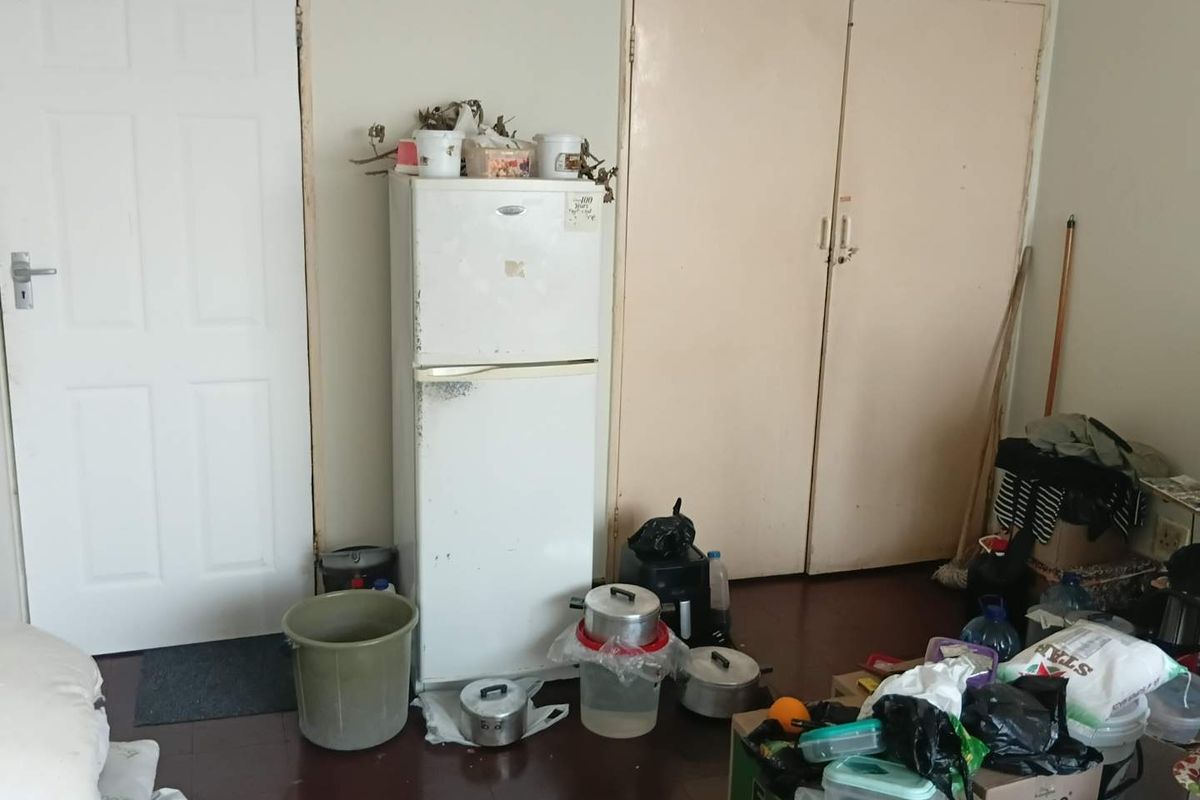 A bedroom featuring built-in cupboards and a standard internal door, currently showing signs of significant wear and requiring maintenance.