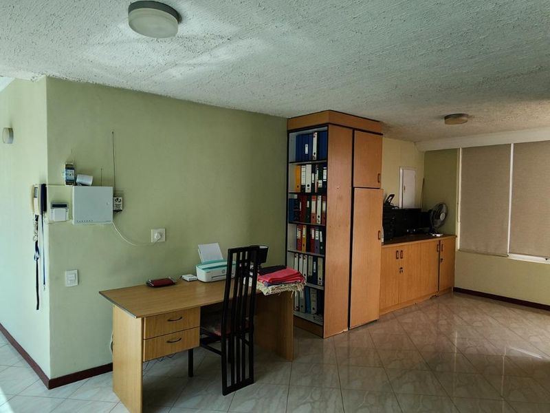 A functional home office space featuring built-in cabinetry, tiled flooring, and natural light from large windows.