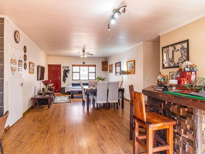 Spacious open-plan living and dining area featuring laminate flooring, a custom built-in bar, and integrated ceiling lighting.