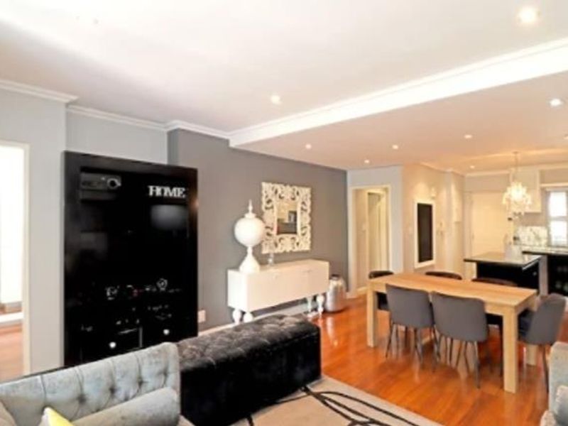Spacious open-plan living and dining area featuring hardwood flooring, recessed lighting, and a modern kitchen with a central island.