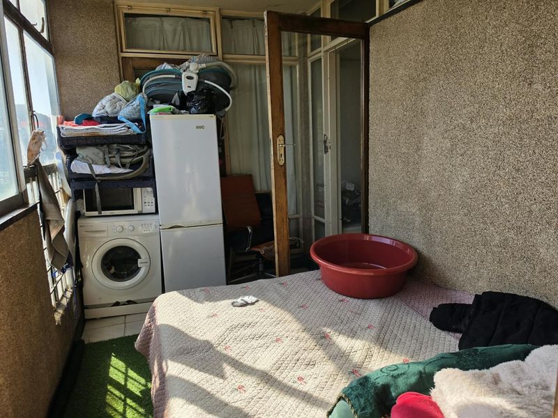An enclosed balcony area featuring pebble dash walls and sliding glass doors, currently utilized as a multi-purpose utility and storage space.