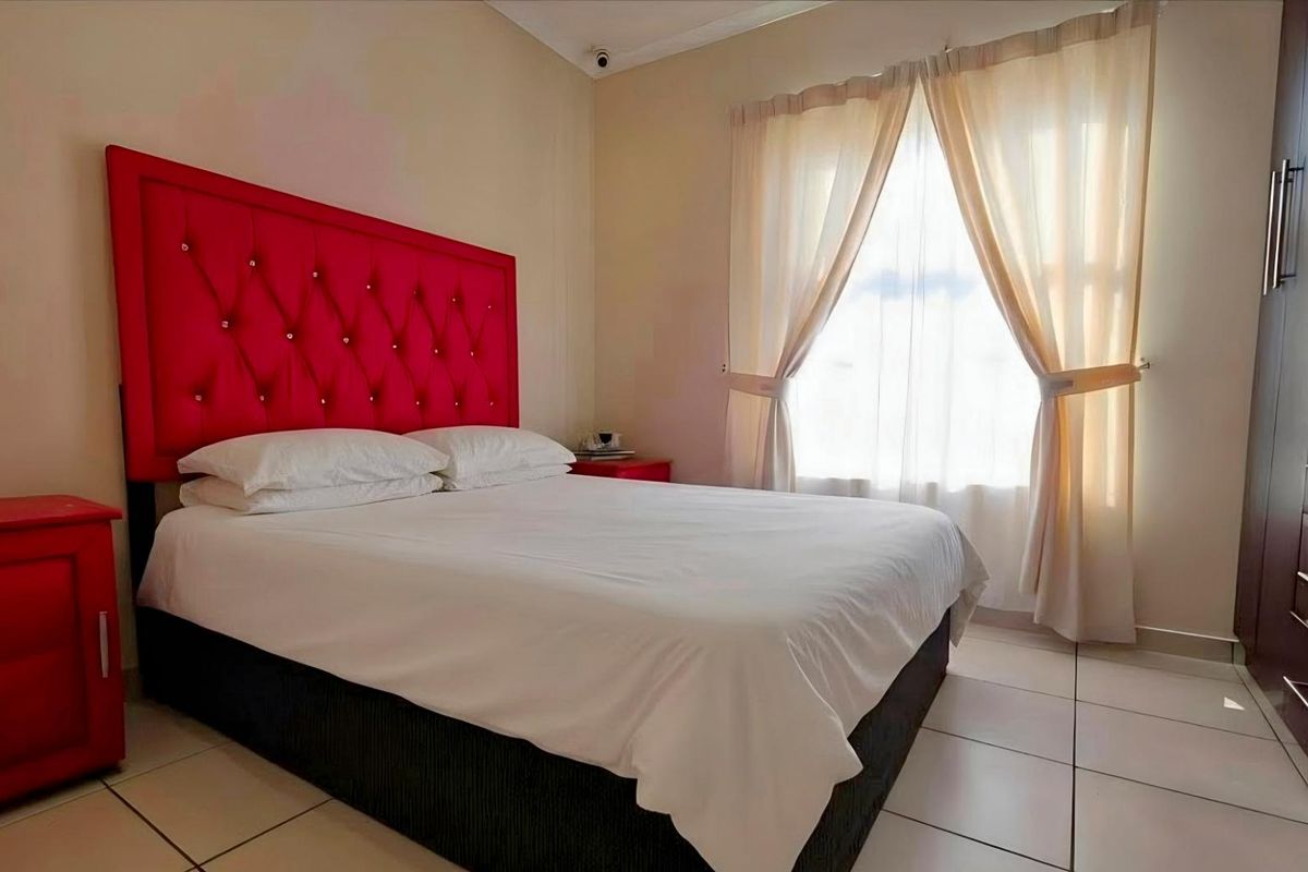 A bedroom featuring tiled flooring and a built-in wardrobe, offering a functional space with natural light from the window.