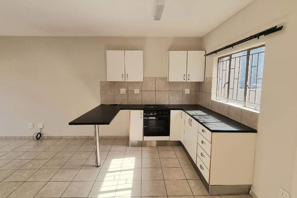 A functional kitchen featuring white cabinetry, dark countertops, a built-in oven and hob, and tiled flooring throughout.