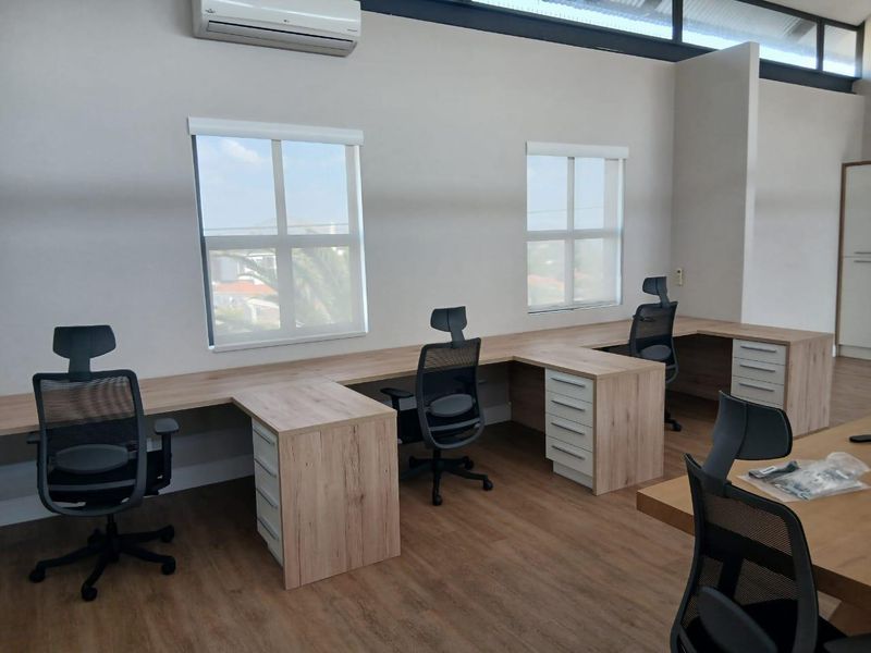 A modern, well-lit office space featuring built-in workstations, laminate flooring, and split-system air conditioning, providing a professional and functional work environment.