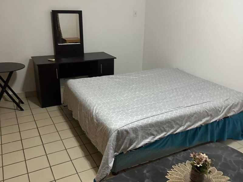 A simple bedroom featuring neutral walls and ceramic tiled flooring, offering a functional space ready for personalization.