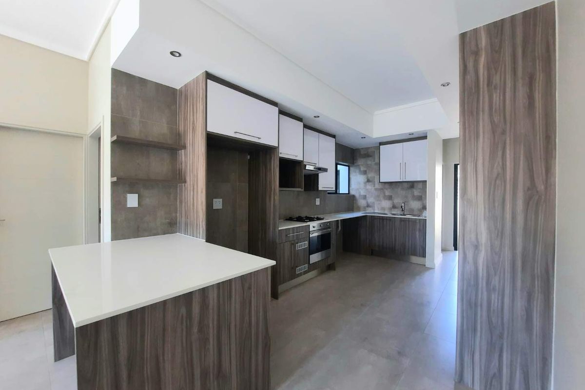 Modern kitchen featuring sleek wood-grain cabinetry, stone countertops, built-in oven, gas hob, and a tiled backsplash in a clean, contemporary layout.