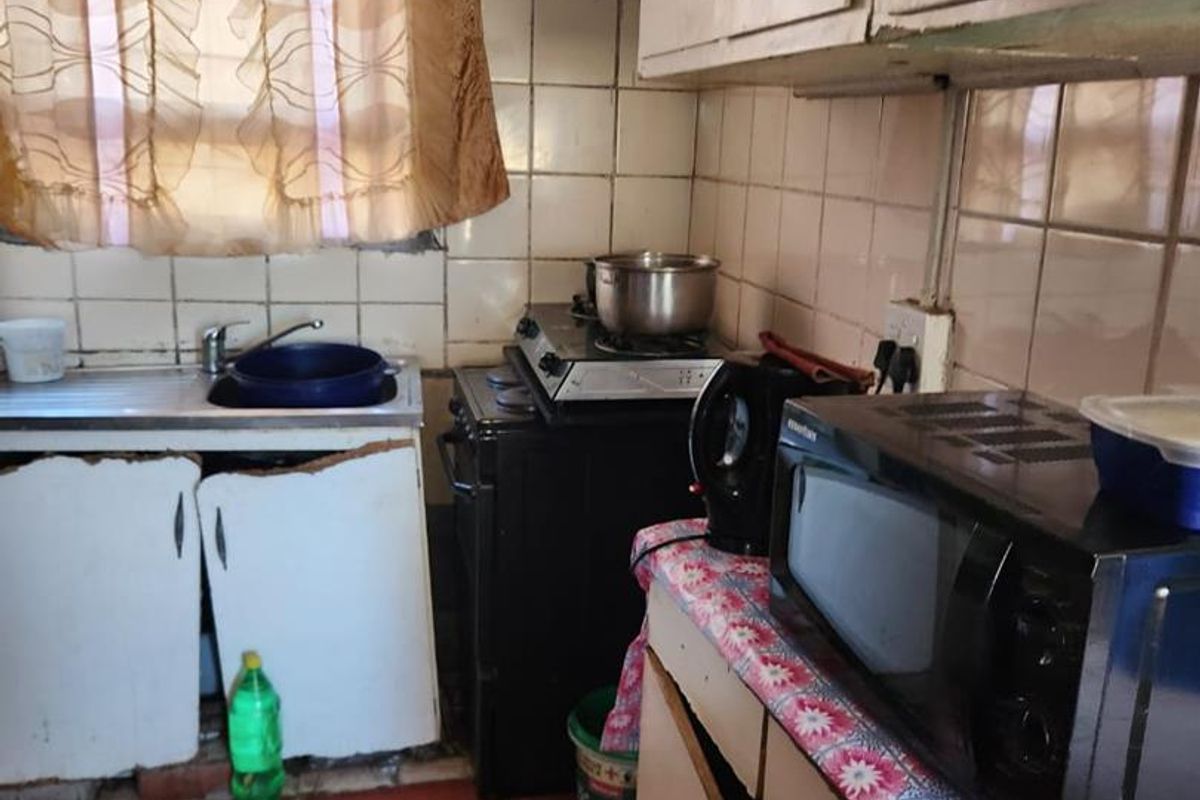 A dated kitchen featuring original cabinetry, tiled splashbacks, and floor tiles, requiring significant renovation and modernization of fixed finishes.