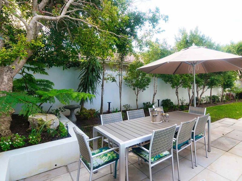 A well-maintained paved patio area featuring a raised garden bed and boundary wall, providing a pleasant outdoor dining space.