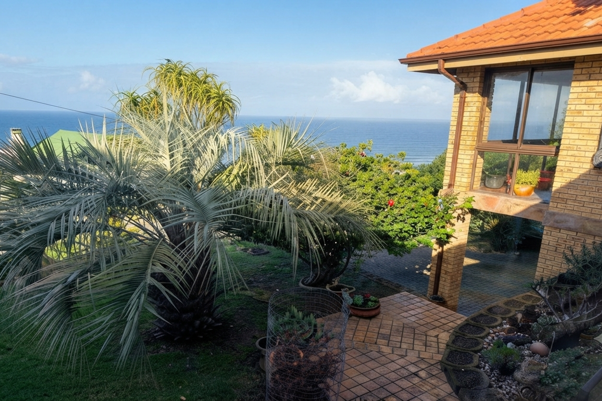 Rear view of a brick house featuring a tiled patio area, established garden, and expansive ocean views.