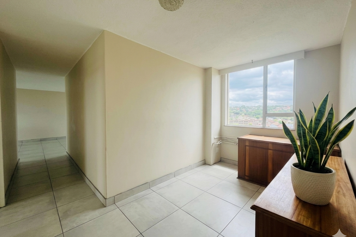A bright, empty living area featuring large windows with neighborhood views, neutral tiled flooring, and a clean, minimalist layout ready for personalization.