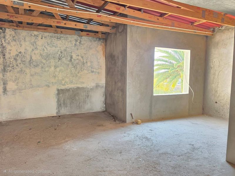 An unfinished interior space featuring exposed timber roof trusses, cement screed flooring, and raw plastered walls, offering a blank canvas for renovation.