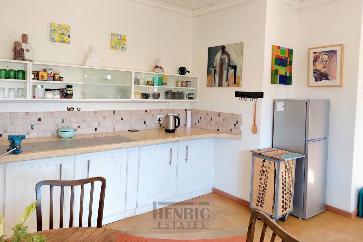 A functional kitchen featuring white cabinetry, tiled backsplash, and laminate countertops, providing a practical workspace with ample wall-mounted storage shelving.