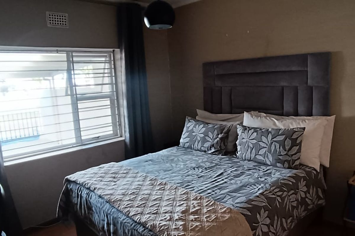 A bedroom featuring a window with security bars and a built-in headboard.
