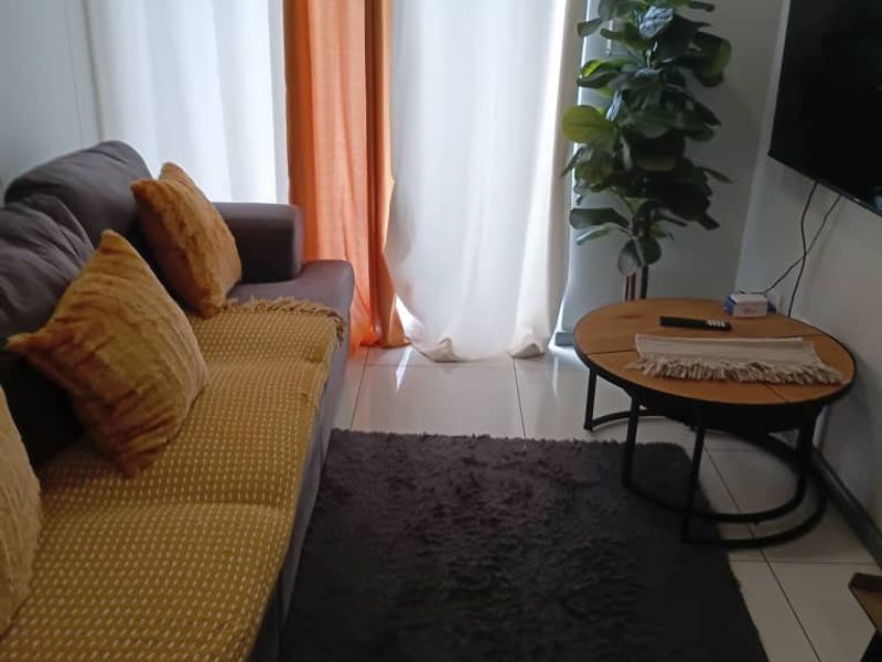 A compact living room area featuring tiled flooring and a sliding door providing access to the exterior.