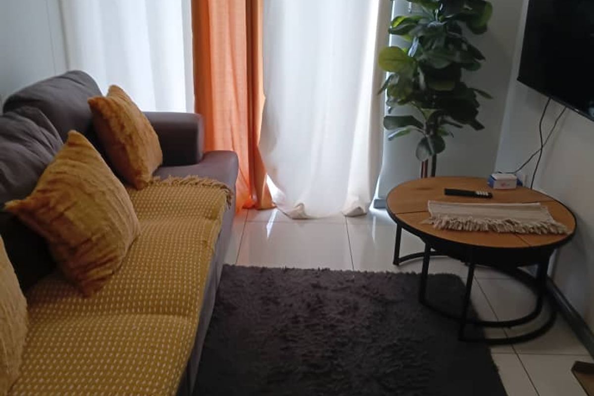 A compact living room area featuring tiled flooring and a sliding door providing access to the exterior.