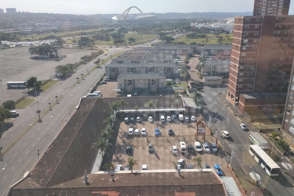 Elevated aerial view overlooking the surrounding urban landscape, parking facilities, and nearby residential apartment complexes.