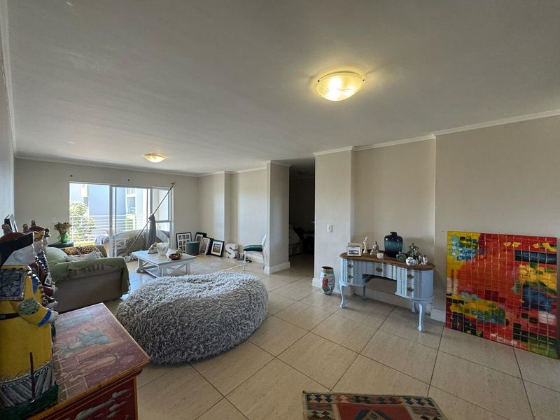 Spacious open-plan living area featuring neutral tiled flooring, coving, and large sliding glass doors providing access to the balcony.
