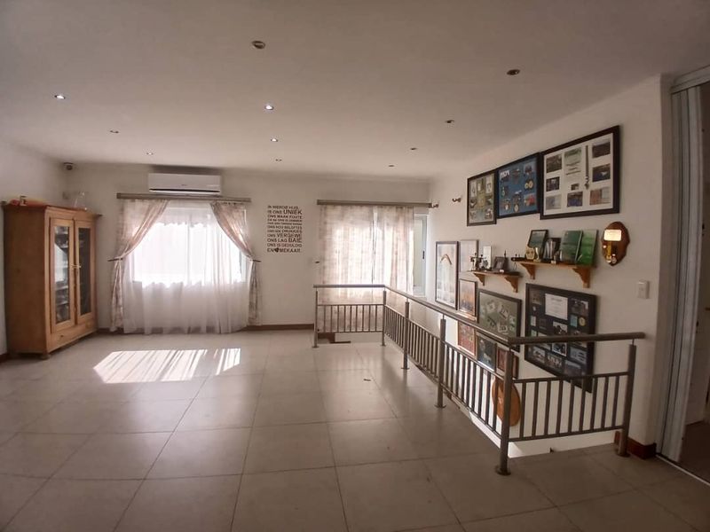 Spacious living area featuring tiled flooring, recessed downlighting, a split-system air conditioner, and a metal balustrade overlooking the lower level.