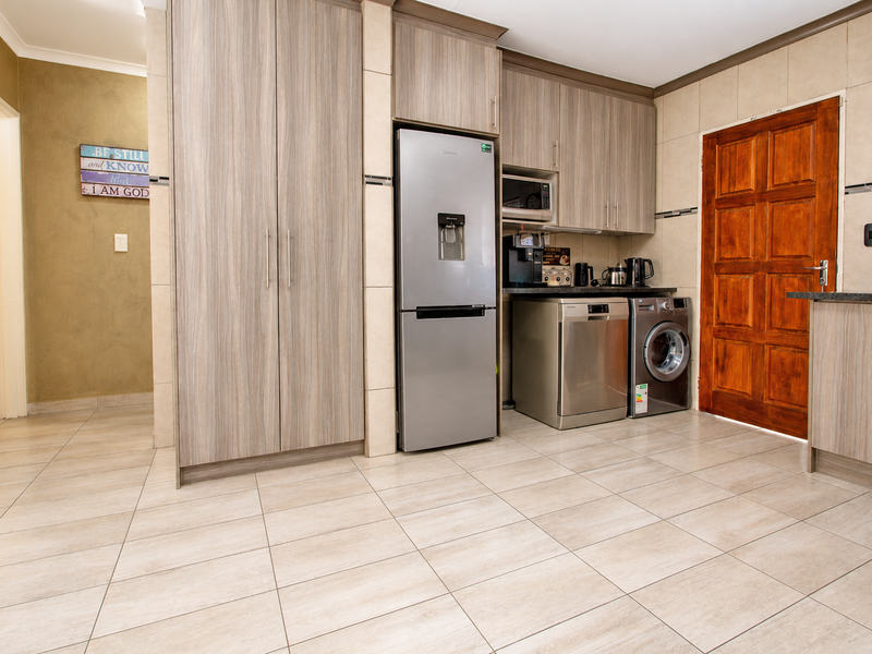 A functional kitchen featuring wood-look cabinetry, tiled flooring, and integrated appliances, providing a clean and practical workspace.
