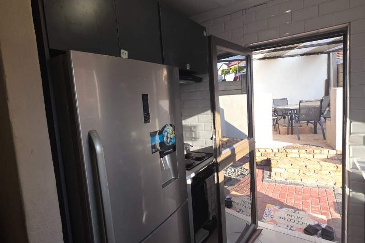 Compact kitchen area featuring dark cabinetry and tiled flooring, with direct access to an outdoor patio space.