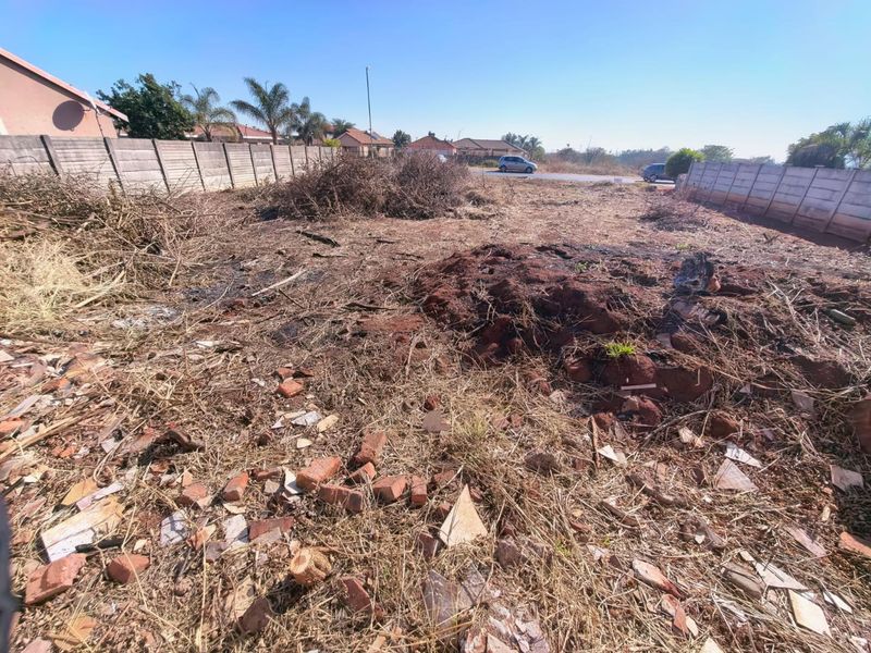 A vacant residential plot featuring precast concrete boundary walls, requiring site clearing and debris removal to prepare for development.