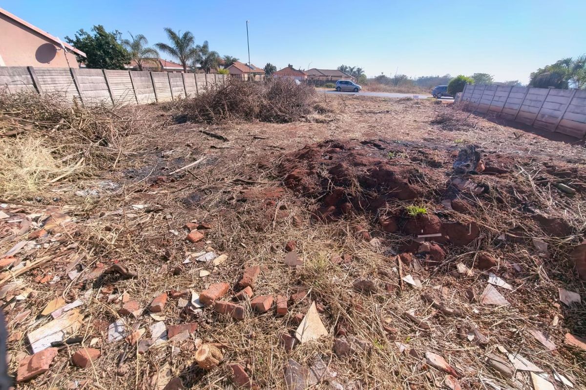 A vacant residential plot featuring precast concrete boundary walls, requiring site clearing and debris removal to prepare for development.