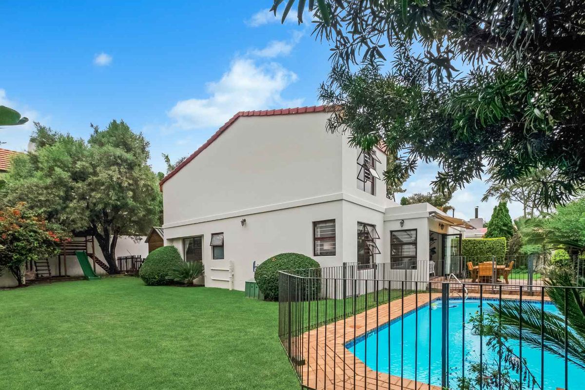 Rear view of the property featuring a well-maintained lawn, a fenced swimming pool, and a paved patio area.