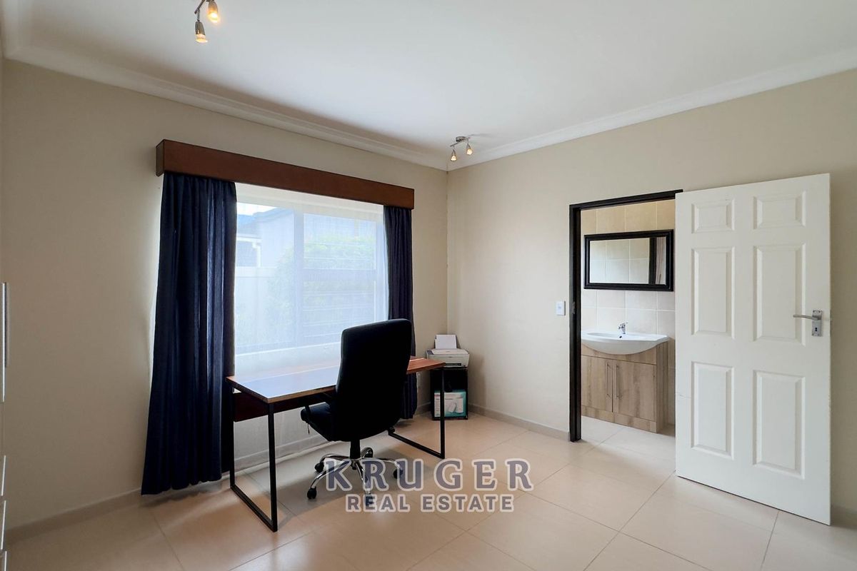 A bedroom featuring tiled flooring, built-in cupboards, and an en-suite bathroom with a vanity unit.